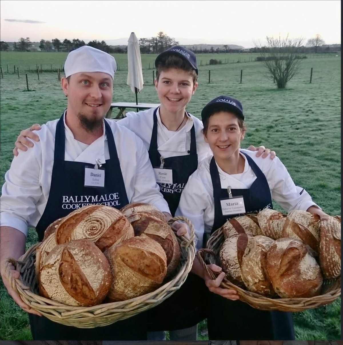 Daniel Lubin with two classmates at Ballymaloe Cookery School, holding baskets of bread they baked.